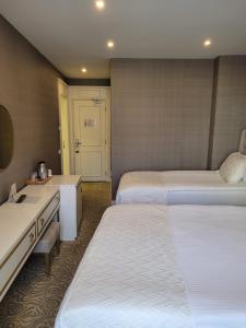 a hotel room with two beds and a desk at Mr Beyaz Hotel Sisli Istanbul in Istanbul