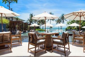 a patio with a table and chairs and umbrellas at Cape Nidhra Hotel - SHA Extra Plus in Hua Hin