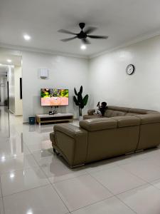 ein Wohnzimmer mit einem braunen Sofa und einem TV in der Unterkunft Roomah Istana in Ipoh