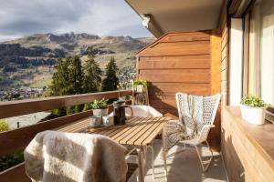 una mesa de madera y sillas en un balcón con vistas en La Ruinette - Modern 1 Bed, 3 Mins From Cable Car, en Verbier