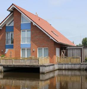 una casa en el agua con un muelle en Ferienwohnung Seegang 25493, en Weener