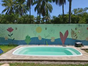 una piscina frente a una valla con un mural en Cafofo de Dri en Ilha de Boipeba