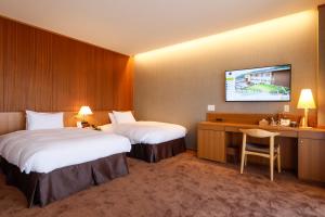 una camera d'albergo con due letti e una TV a parete di Hotel Nara Sakurai No Sato a Sakurai