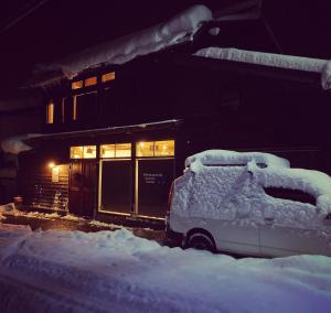 ein schneebedecktes Auto vor einem Gebäude in der Unterkunft GuestHouse Shirakawa-Go INN in Shirakawa-gō