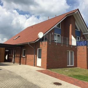 una casa in mattoni con tetto rosso e balcone di Ferienwohnung Landgang 25494 a Weener