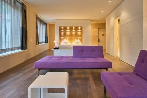 a hotel room with purple couches and a bed at Limmathof Baden - Boutique Haus & Spa in Ennetbaden +21 photos