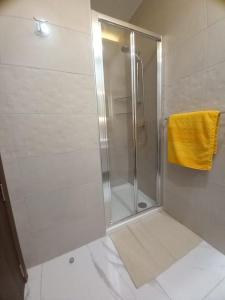 La salle de bains est pourvue d'une douche et d'une serviette jaune. dans l'établissement Brand new 1 bedroom studio flat, à Gudja