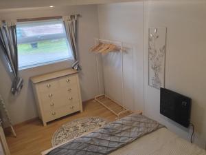 een slaapkamer met een bed, een dressoir en een raam bij Foxs Lair Aberdovey in Aberdyfi