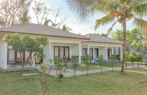 a house with palm trees in the yard at Nusa Indah Bungalows in Gili Islands