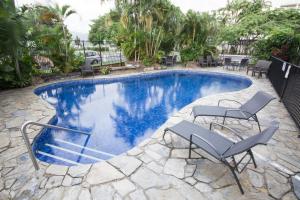 a swimming pool with two chairs and a table at Cairns Plaza Hotel in Cairns