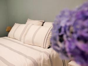 ein Bett mit weißen Kissen und einem Blumenstrauß in der Unterkunft Gîte du vieux chêne - 6pers. - Jardin arboré in Ault