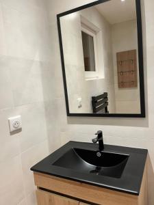 een badkamer met een zwarte wastafel en een spiegel bij Chalet Gentiane in Gérardmer