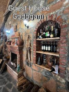 een kamer met een bakstenen open haard en een bos wijnflessen bij Guest House Godogani in Godogani