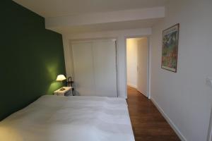 - une chambre avec un lit blanc et un mur vert dans l'établissement RHUNE ET MER AVEC LES CLES DE LUZ, à Saint-Jean-de-Luz