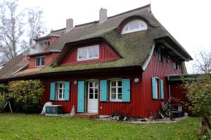 a red house with a thatched roof at Krabbenkate in Prerow