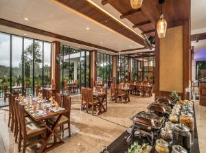 restauracja ze stołami i krzesłami oraz dużymi oknami w obiekcie WILD AVENUE RESORT & SPA w mieście Thekkady