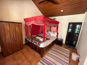 a bedroom with a bed with a canopy and a rug at Jardim a Mar in Agonda