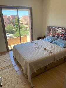 a bedroom with a bed and a large window at Prestigia jade Marrakech ENTREE 191 APPARTEMENT 9 in Marrakech