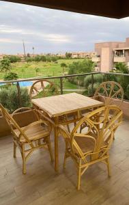 y balcón con mesa y sillas de madera. en Prestigia jade Marrakech ENTREE 191 APPARTEMENT 9 en Marrakech