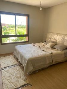 a large bed in a room with a window at Prestigia jade Marrakech ENTREE 191 APPARTEMENT 9 in Marrakesh