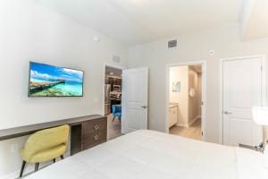 a white bedroom with a bed and a desk and chairs at 4013 Vista Cay 2 in Orlando