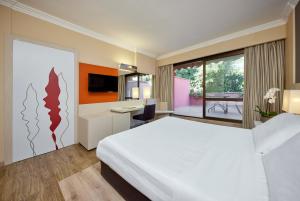 a bedroom with a large white bed and a desk at Park Hotel I Lecci in San Vincenzo
