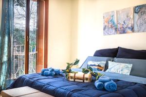1 cama con sábanas azules en una habitación con ventana en PURA VIDA APARTMENT Porto Torchio, en Manerba del Garda