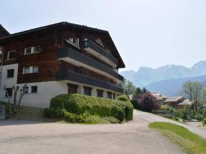 a building with a bush next to a road at Appartement Le Grand-Bornand, 3 pièces, 6 personnes - FR-1-241-62 in Le Grand-Bornand
