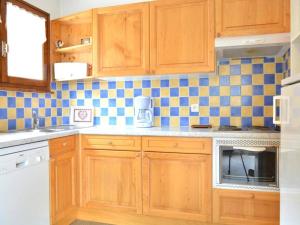eine Küche mit Holzschränken und blauen und weißen Fliesen in der Unterkunft Appartement Le Grand-Bornand, 2 pièces, 6 personnes - FR-1-241-106 in Le Grand-Bornand