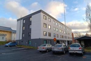 a building with cars parked in a parking lot at Style 1BR Appartment in Tornio in Tornio