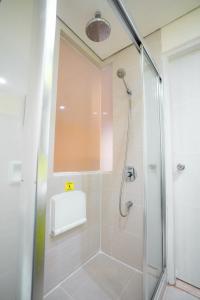 een badkamer met een douche en een glazen deur bij MaxOneHotels.com at Vivo Palembang in Palembang