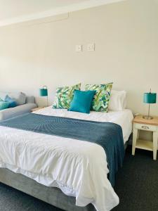 1 dormitorio con 1 cama blanca grande con almohadas azules en Port Edge - Ships Bell, Port St Francis Bay, en St Francis Bay