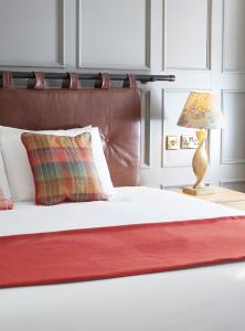 a bed with a red blanket and a lamp on a table at Castle Hotel by Chef & Brewer Collection in Leicester