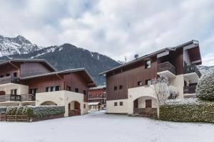 um grupo de edifícios na neve com montanhas em Les Jardins du Mont-Blanc - Happy Rentals em Chamonix-Mont-Blanc