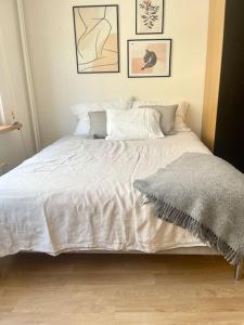 1 dormitorio con cama blanca y manta gris en Lovely studio in the famous Design District area., en Helsinki