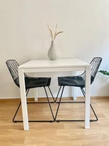 a white table with two chairs and a vase on it at Lovely studio in the famous Design District area. in Helsinki