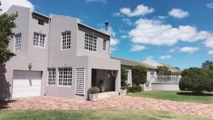 a large white house with a driveway at Lemon Tree Cottage in Edgemead
