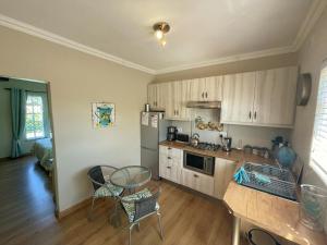 una cucina con mobili bianchi, tavolo e sedie di Lemon Tree Cottage a Edgemead