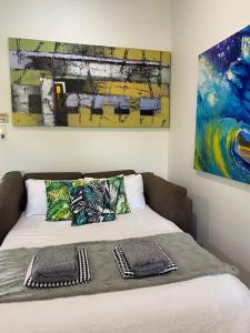 a bed with two pillows and a painting on the wall at Luxury Top Floor Sunset Villa in Noosaville