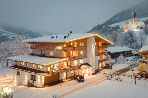 ein großes Gebäude im Schnee mit einem Berg in der Unterkunft Hotel Garni Romantik in Fügen