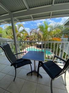 a table and two chairs on a balcony with a pool at Luxury Top Floor Sunset Villa in Noosaville