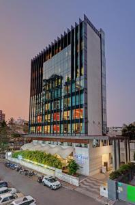 a tall building with cars parked in a parking lot at The Fern Residency Mumbai in Mumbai