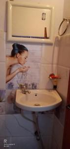una mujer en un baño bebiendo de un lavabo en UGS guest house en Jodhpur