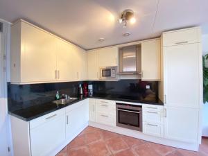 une cuisine avec des armoires blanches et des comptoirs noirs dans l'établissement Callantsoger Staete A212, à Callantsoog 4 autres photos