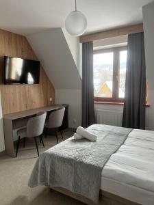 a bedroom with a bed and a desk and a window at Willa Joanna in Białka Tatrzanska