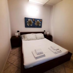 a bedroom with a bed with white sheets and flowers on the wall at Appartamento Pizzo di Parlasco - Your Mountain Holiday in Taceno