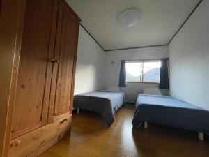 a small bedroom with two beds and a window at Five Peaks Ryuoo in Shimotakai