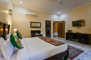 a hotel room with a bed and a television at Dev Garh in Jaisalmer