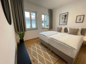 a bedroom with a large bed and two windows at Gmund Seeliebe Premiumsuite in Gmund am Tegernsee