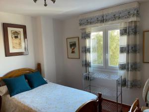 - une chambre avec un lit doté d'oreillers bleus et d'une fenêtre dans l'établissement Apartamento Ravel Playa Málaga, à Malaga